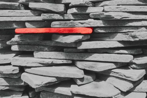 One red stone among the gray stones. Gray stones are stacked one on another. Stock Photos