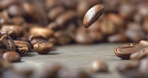 One roasted coffee bean falling onto wooden table in super slow motion Stock Footage 344848453
