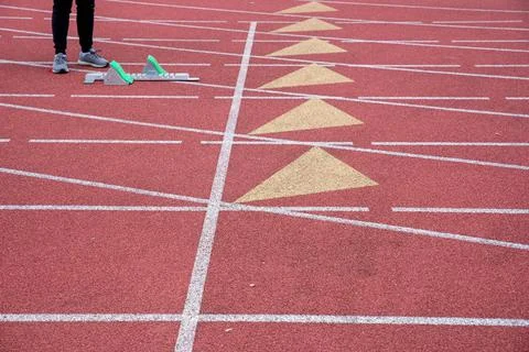 One runner stands by a starting block on an empty athletic track Stock Photos