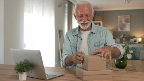 One senior man open box presents and read card while on video call Stock Footage 250208599