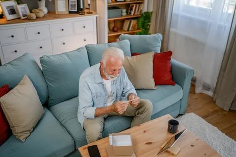 One senior man open box presents and read card while on video call Stock Photos