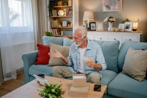 One senior man open box presents and read card while on video call Stock Photos