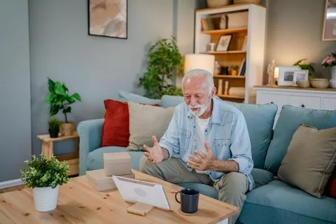 One senior man open box presents and read card while on video call Stock Photos