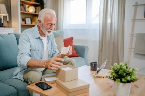 One senior man open box presents and read card while on video call Stock Photos