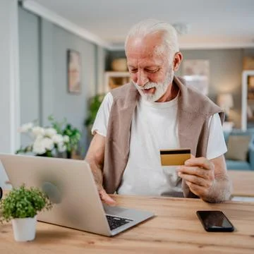 One senior man use laptop computer hold credit car shopping online Stock Photos