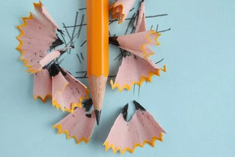 One sharp graphite pencil and shavings on light blue background, top view 写真素材