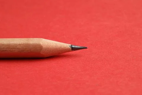 One sharp graphite pencil on red background, closeup 스톡 사진