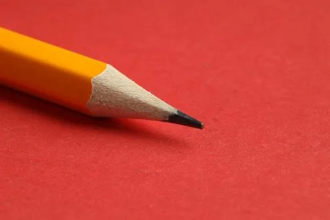 One sharp graphite pencil on red background, closeup. Space for text 写真素材