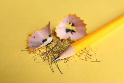 One sharp graphite pencil, scribbles and shavings on yellow background, close Stock Photos