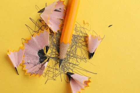 One sharp graphite pencil, scribbles and shavings on yellow background, top.. Stock Photos