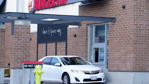 One side of Burger King drive thru with car buying food and paying credit card Video stock 75048741