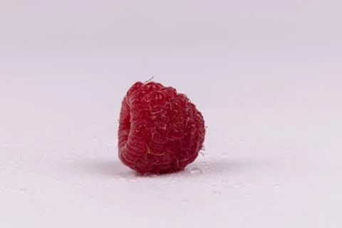 One side of red raspberry splattered with water on white background Stock Photos