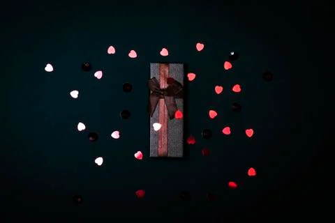 One single gift wrapped in dark brown paper with a bow of packthread on black Stock Photos