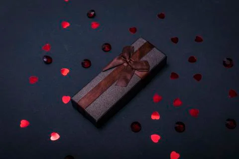 One single gift wrapped in dark brown paper with a bow of packthread on black Foto stock