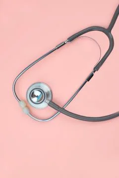 One single normal stethoscope isolated on top of a pink color paper backgroun Stock Photos
