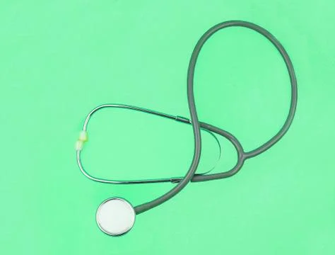 One single normal stethoscope isolated on top of a green color paper backgrou Stock Photos
