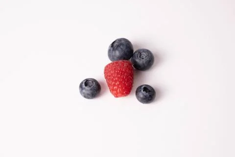 One single raspberry and blueberry lie on a table Stock Photos