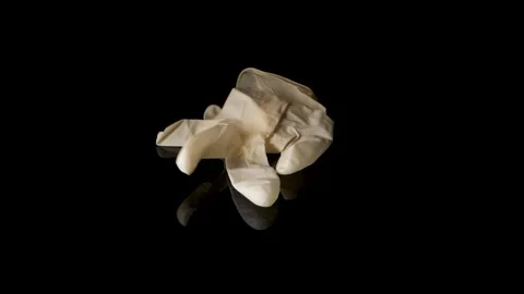 One single use glove is falling in slow motion on black surface, isolated Stock Footage 147375605