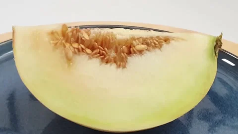 One slice of honeydew melon with seeds on top of spinning turntable. Stock Footage 159830501