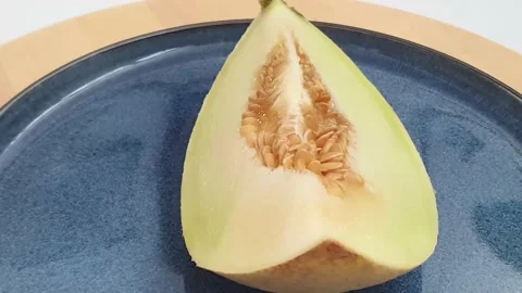 One slice of honeydew melon with seeds on top of spinning turntable. Video stock 159830515