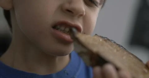 One small boy taking a bite of toast bread, close-up child mouth eating car.. Stock Photos