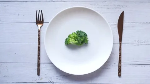 One small green broccoli on white plate with fork and knife isolated on whi.. Stock Footage 332579484