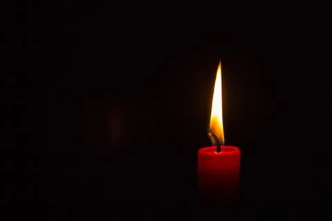 One small lit red candle on a black background Stock Photos