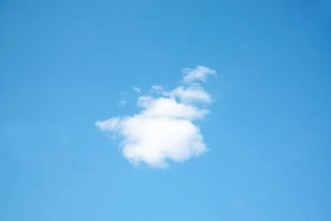 One small white cloud on light blue clear sky at sunny summer day Stock Photos