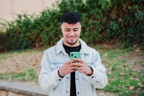 One smiling moroccan guy having fun using a smartphone to play a video game Stock Photos