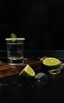 One stack of tequila with fresh lime slices and salt on stylish wooden board Foto stock
