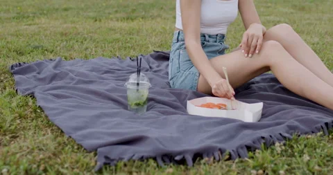 One summer evening at a picnic, a young woman eats sushi rolls of various kinds Stock Footage 201469025