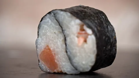 One Sushi Roll is Spinning in a Black Container Close-up Stock Footage 222798053