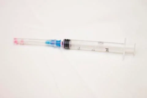 One syringe with cap and needle after using on the white bckground Stock Photos