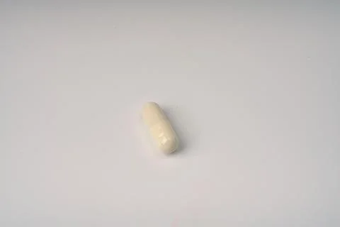 One tablet capsule on a white background closeup. Stock Photos