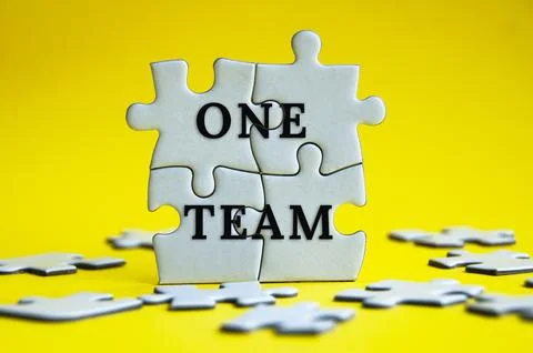 One team text on jigsaw puzzle with yellow background. Teamwork concept Stock Photos