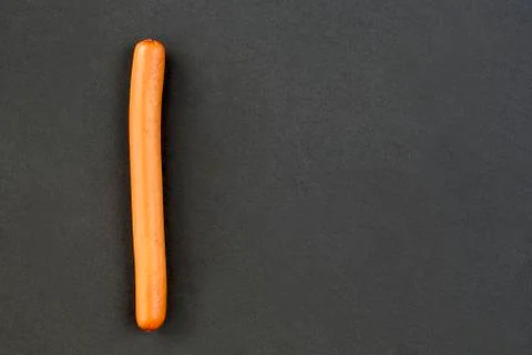 One thin sausage on a dark background Stock Photos