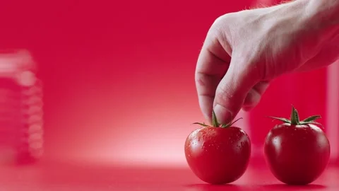 One of the tomatoes lined up on a red background is touched and they move. Stock Footage 132256450