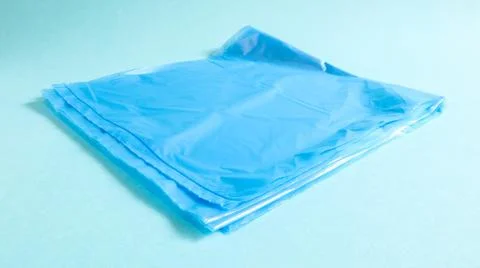 One torn plastic garbage bag in blue on a blue background. A bag that is desi Foto stock