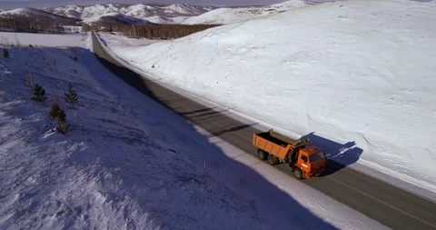 One track rides on an empty snowy road in the mountains Stock Footage 104472383