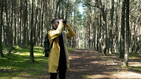 One trendy guy in colorful jacket alone stand in woodland, use optics equipment Stock Footage 199492945