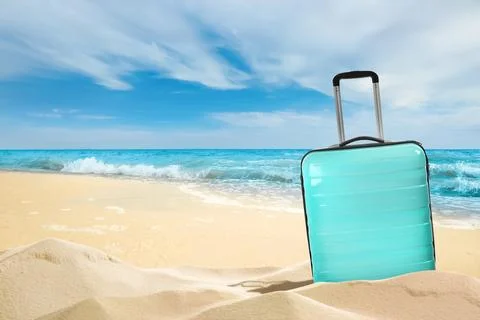 One turquoise suitcase on sandy beach near sea. Space for text Stock-Fotos