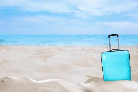 One turquoise suitcase on sandy beach near sea. Space for text Stock-Fotos