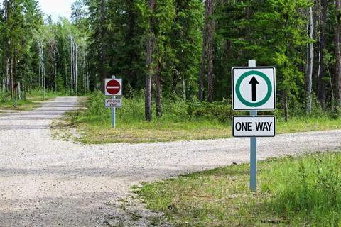 A one way and a wrong way sign by a country road intersection Stock Photos