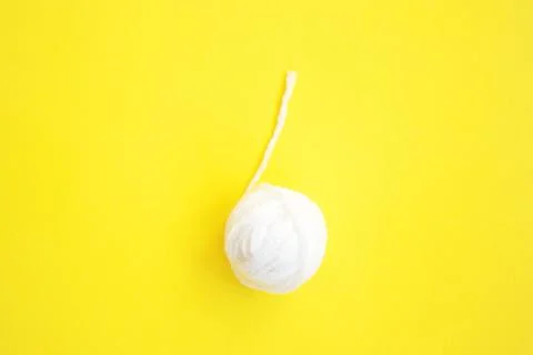 One white ball of woolen thread on yellow background Stock Photos