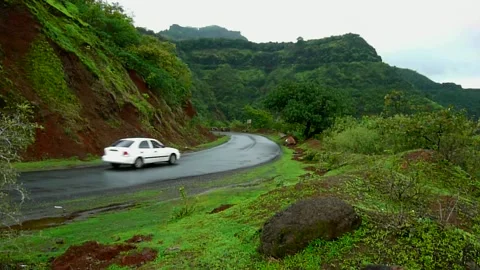 One white car driving on empty wet Monsoon cloudy hill Road Mahabaleshwar India Stock Footage 155983360