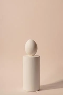 One white Easter egg on a podium against a neutral background. Minimalism and Stock Photos