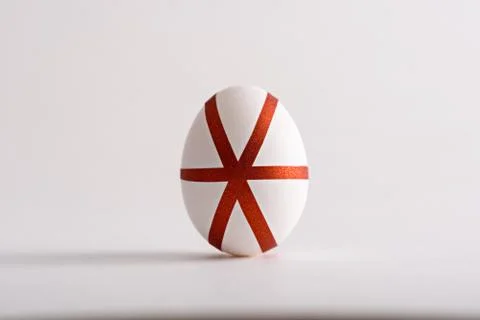 One white Easter egg with red geometric stripes on white background Stock Photos