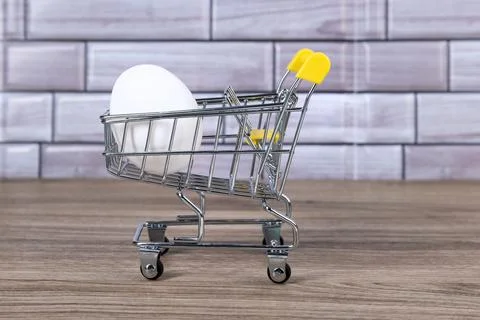 One white egg in a tiny shopping cart Foto stock