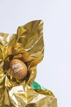 One white egg wrapped in metallic  shiny gold paper on white background Stock Photos
