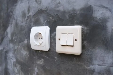 One white electrical power socket and one double light switch mounted on a .. Stock Photos